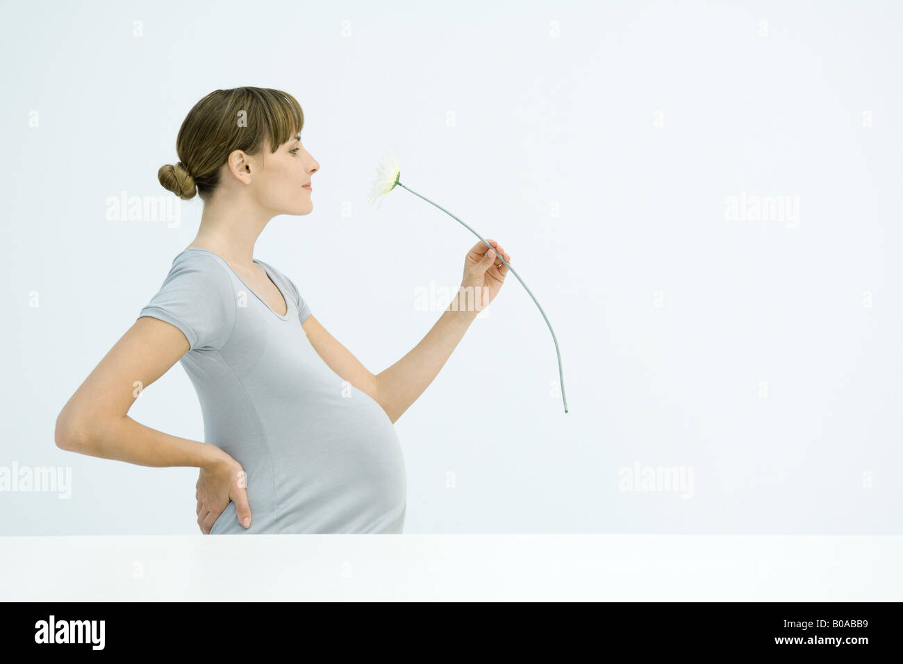 Pregnant woman smelling flower, smiling, side view Stock Photo Alamy