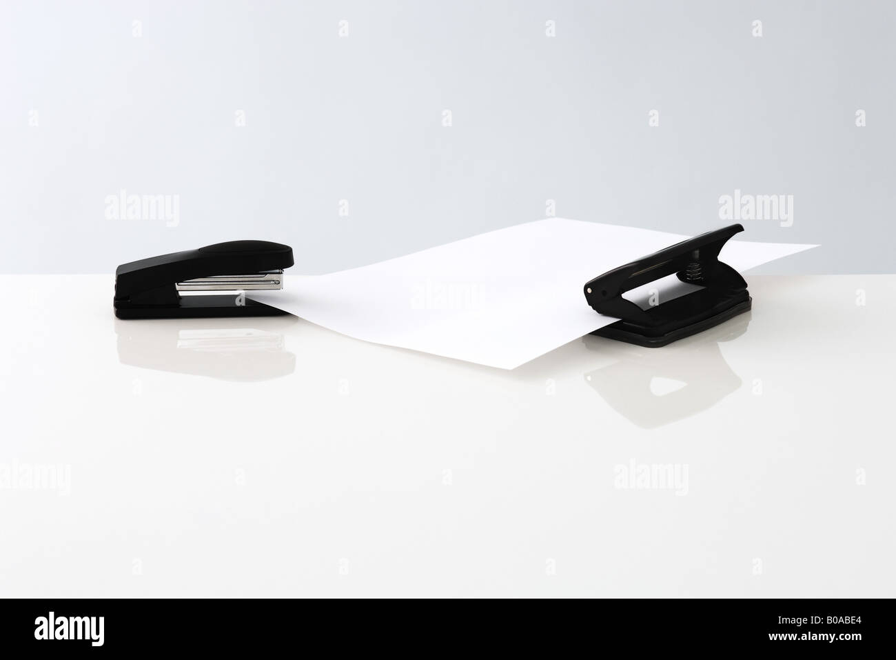 Stapler and hole puncher with single sheet of paper Stock Photo Alamy