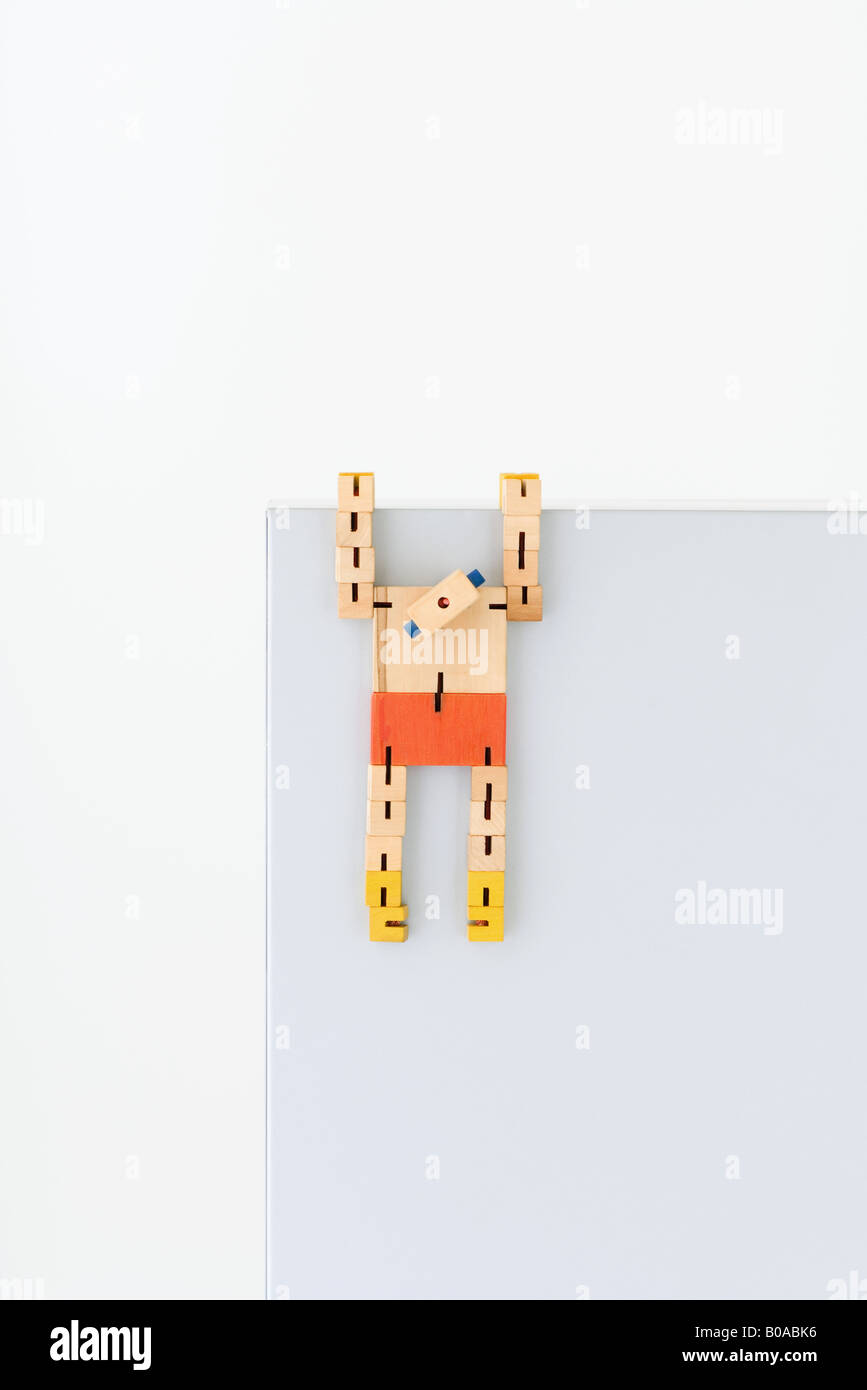 Wooden robot hanging from ledge Stock Photo