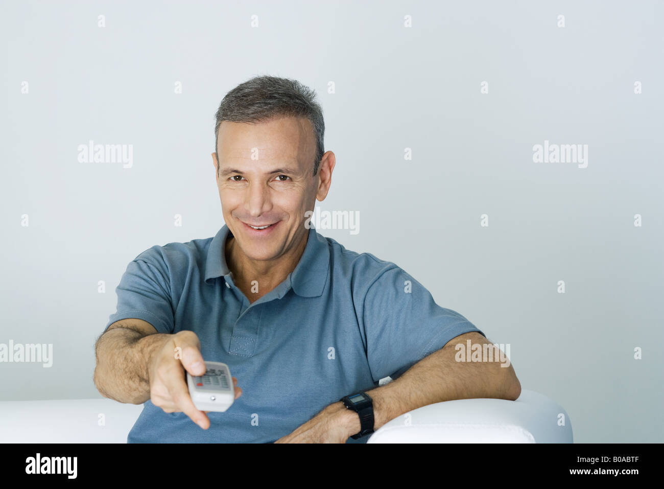 Man holding remote control, smiling at camera Stock Photo