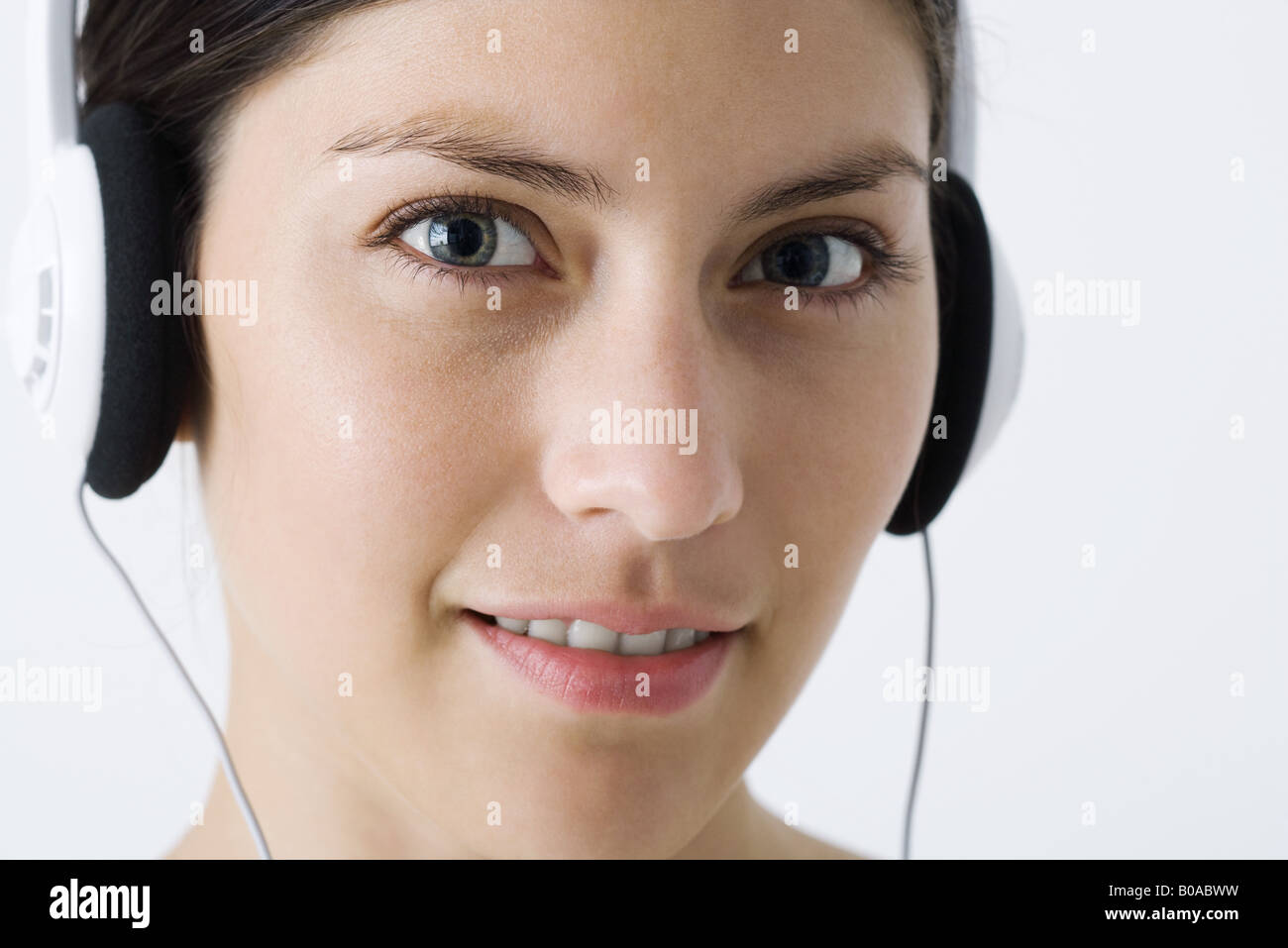 Young woman listening to headphones, looking at camera, close-up Stock ...