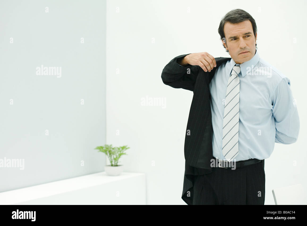 Businessman putting on suit jacket, looking away Stock Photo