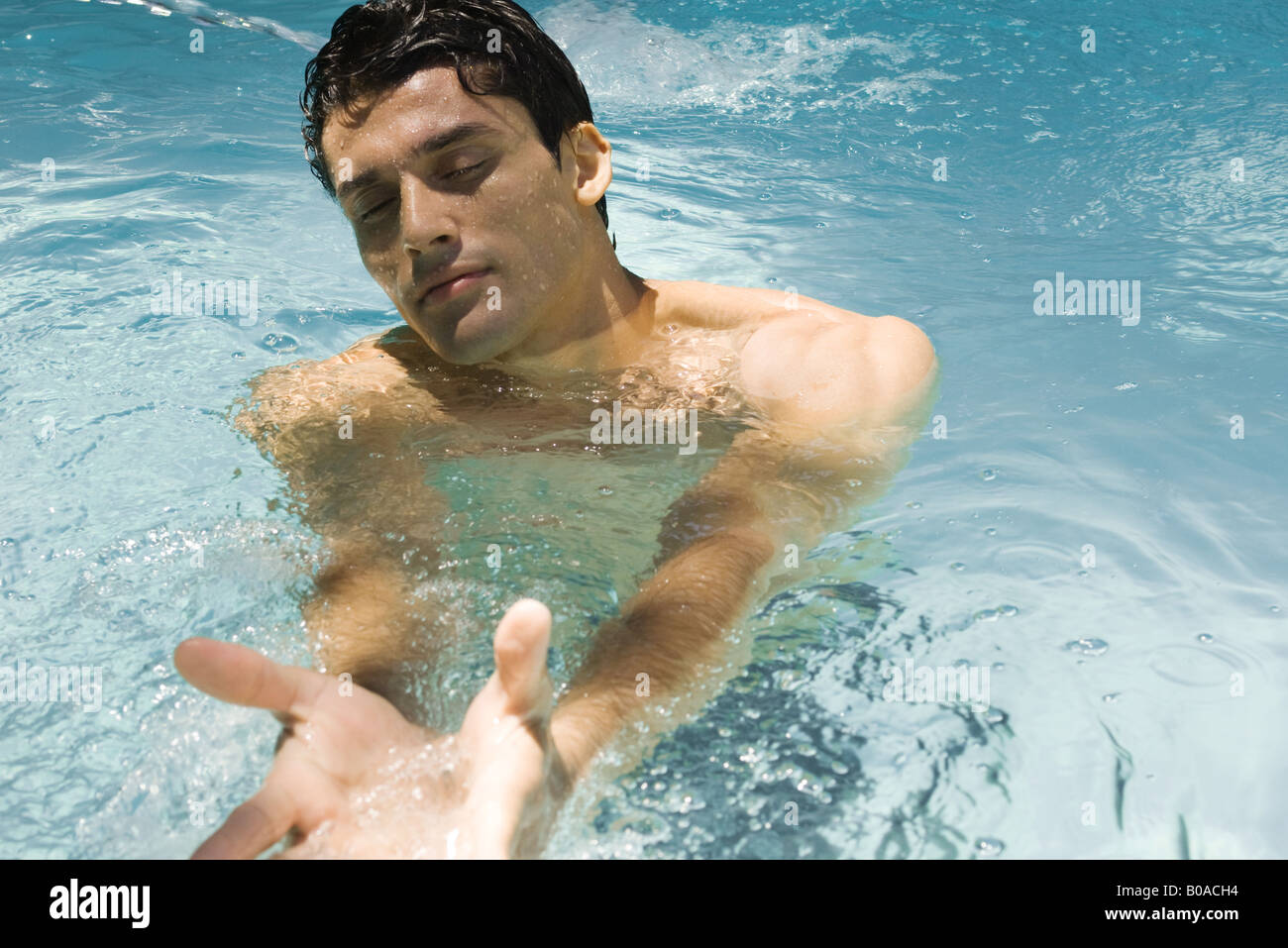 Man in swimming pool, eyes closed, arms outstretched Stock Photo