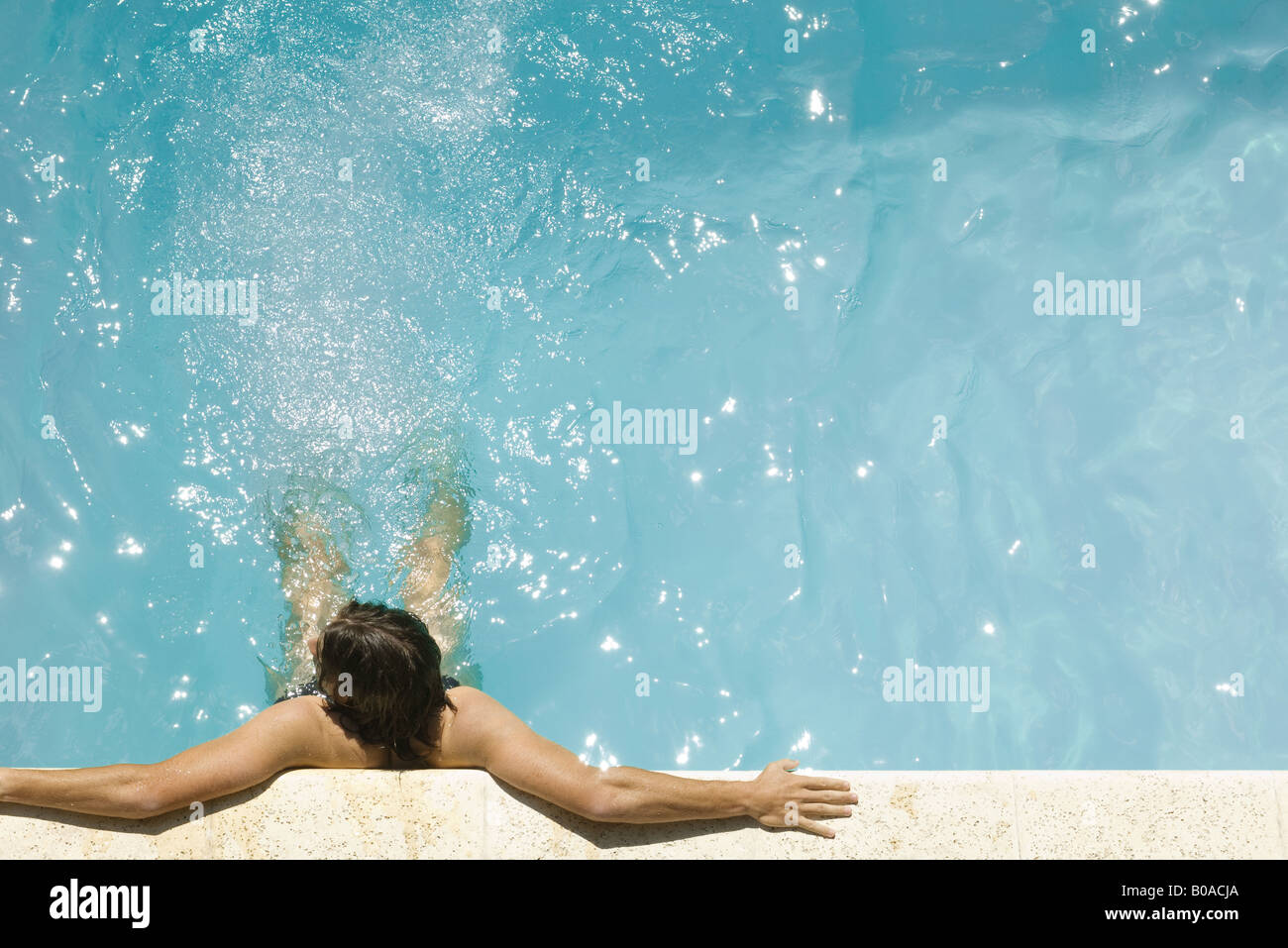 Man in swimming pool, holding on to edge, high angle view Stock Photo