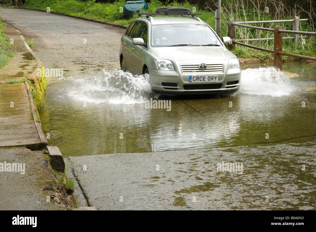 Car driving through a ford with water splashing from the wheels Stock Photo