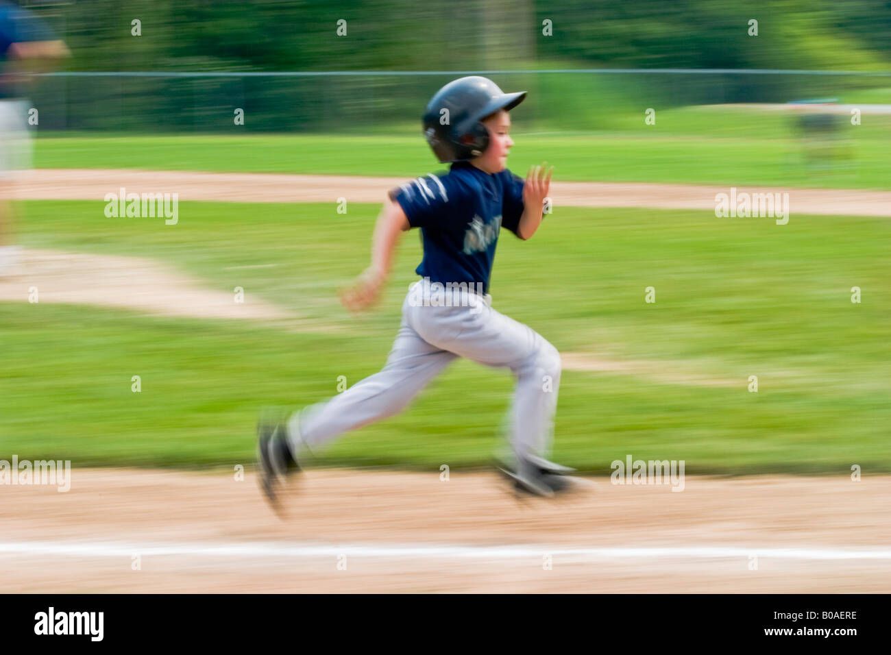 Young boy running from third base to home plate during a Little League