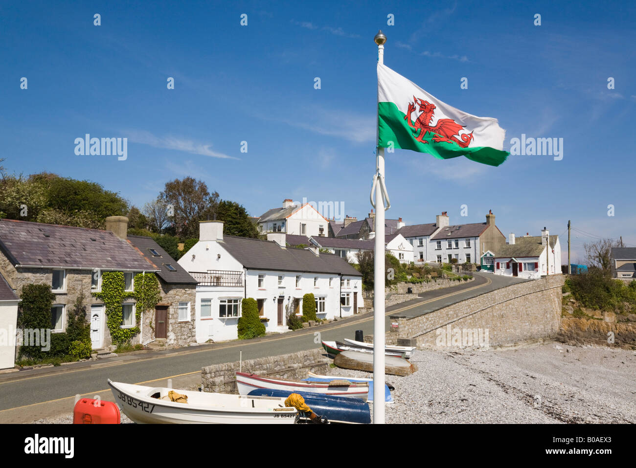Seafront cottages boats on beach with Welsh flag flying in small historic village on coast. Moelfre Isle of Anglesey North Wales UK Britain Stock Photo