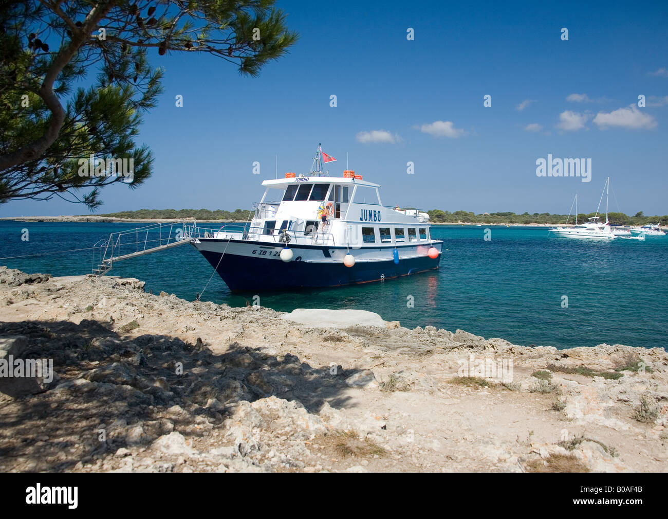 The pleasure boat 'Jumbo' moored in the crystal clear sea at Arenal de Son Saura, Menorca, Ballearic Islands, Spain. Stock Photo