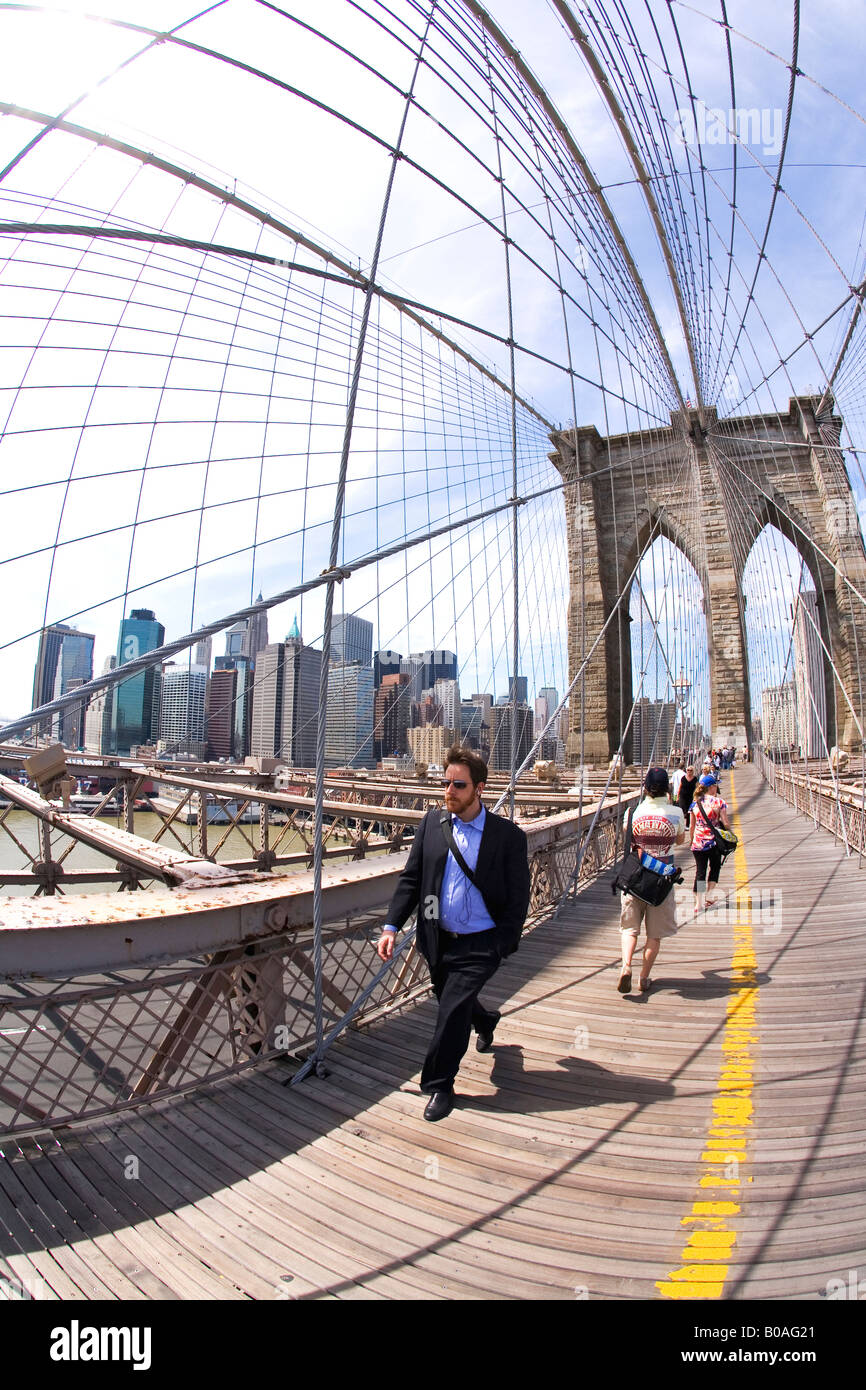 Tourists and New Yorkers pedestrians enjoy walking in sunshine on Brooklyn Bridge Lower Manhattan New York City NYC USA Stock Photo