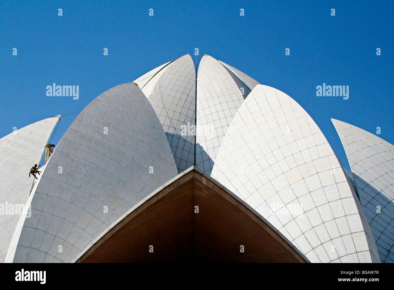 Places of worship - climbers scampering up petal shaped dome roof of the lotus temple - famous landmark in New Delhi Stock Photo