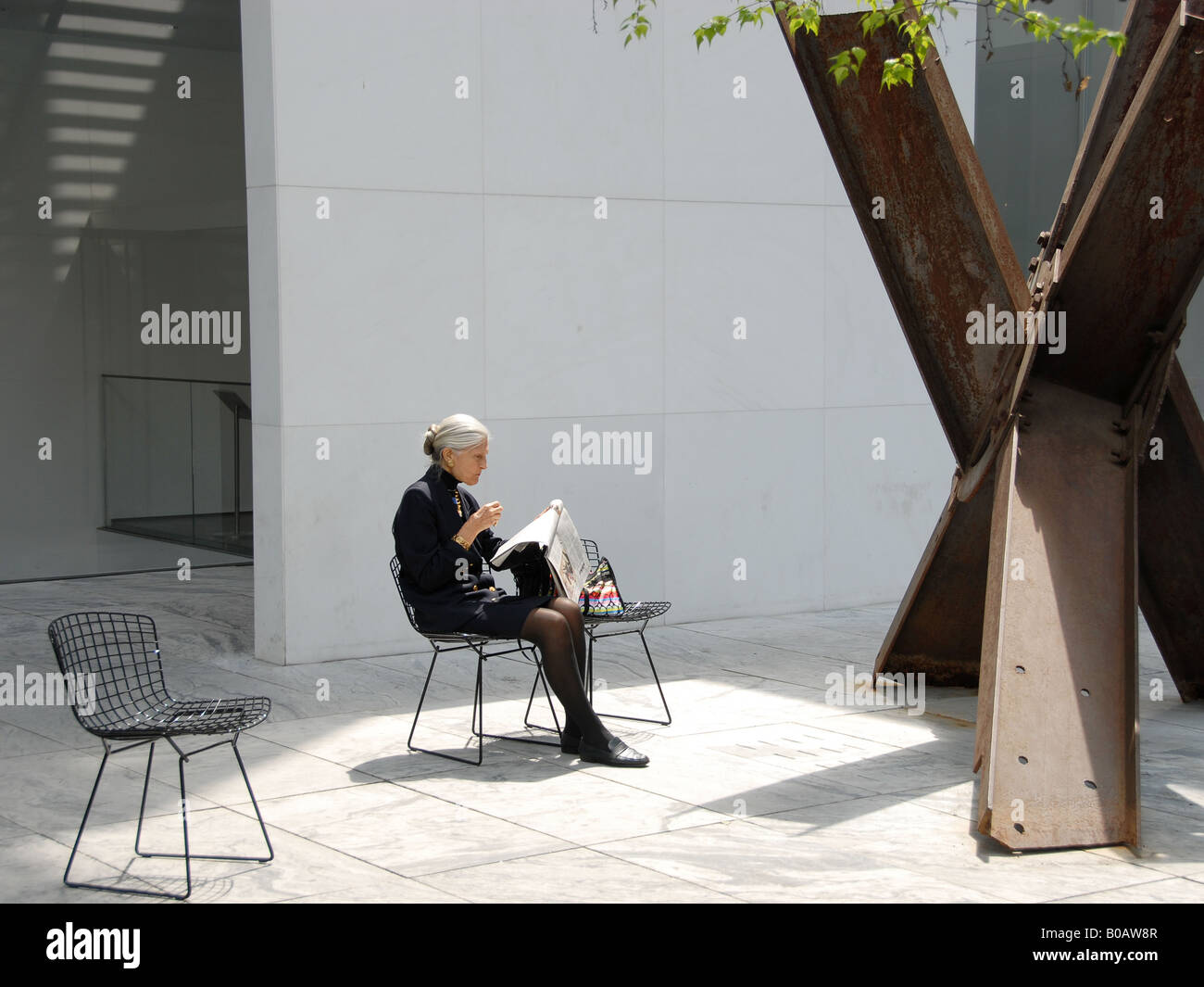 Stilish older lady, reading her newspaper in the MoMa garden 2 Stock Photo