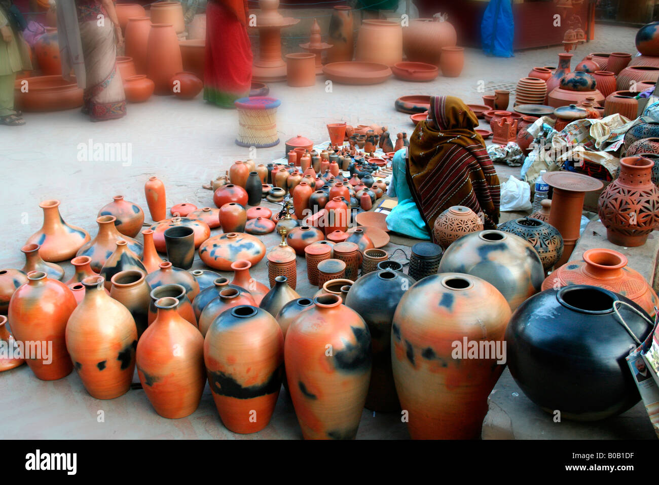 Old woman selling clay ceramic pottery - pots vases jugs - at a winter bazaar or local open-air market in New Delhi India Stock Photo