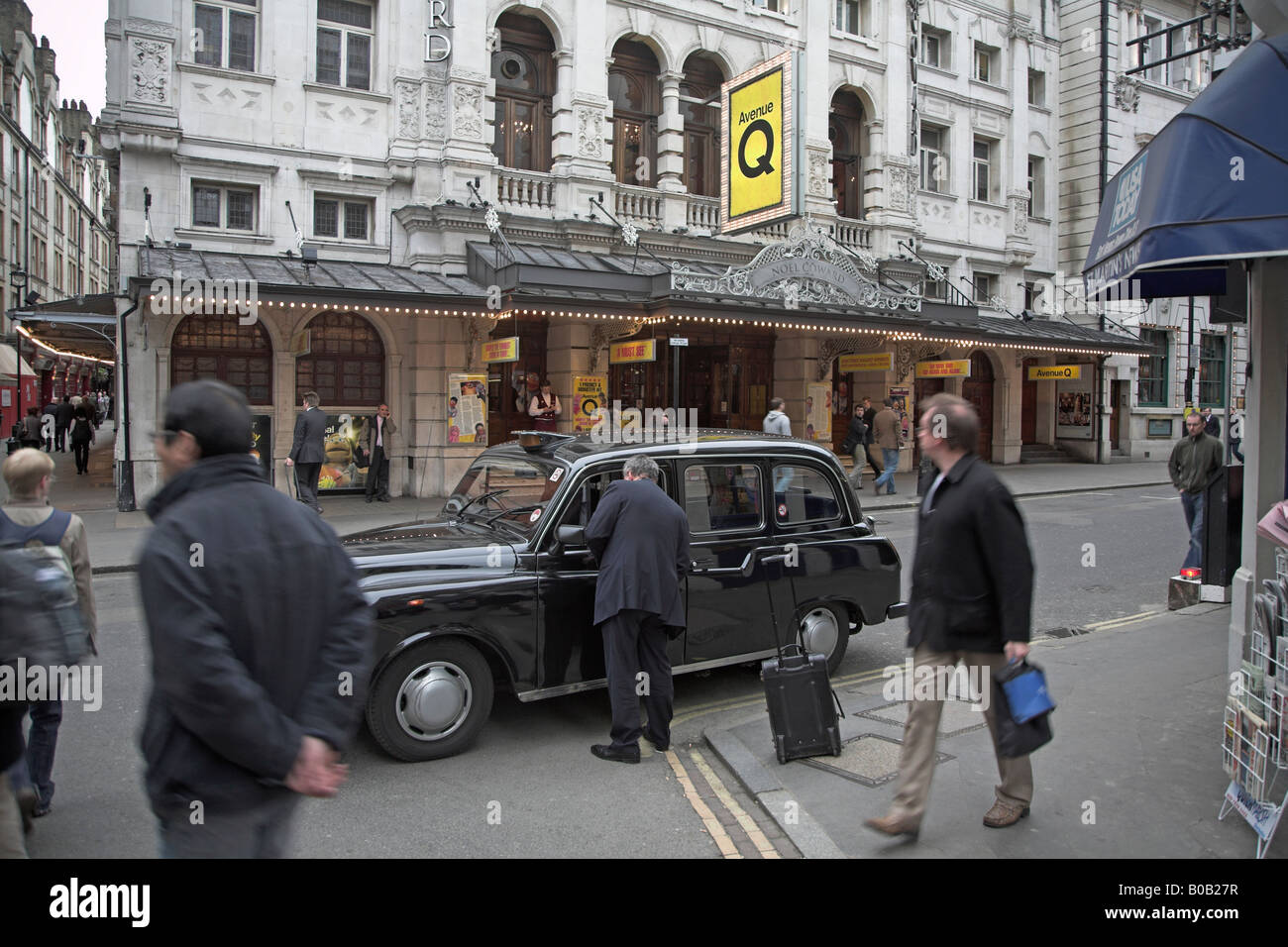 Black taxi pulls up in street opposite Noel Coward theatre, London, England Stock Photo