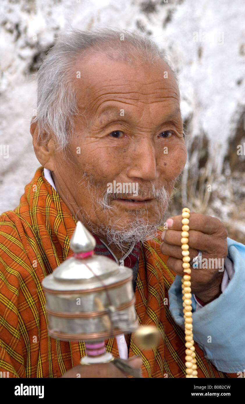 Spectator in traditional dress (gho) with prayer wheel and beads at the Paro Tsechu (festival), Bhutan Stock Photo
