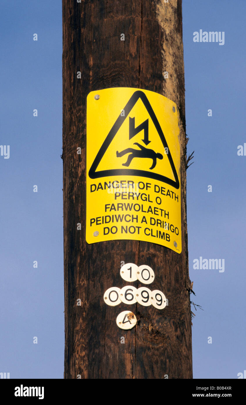 English / Welsh bi-lingual warning sign on electricity pole. Stock Photo