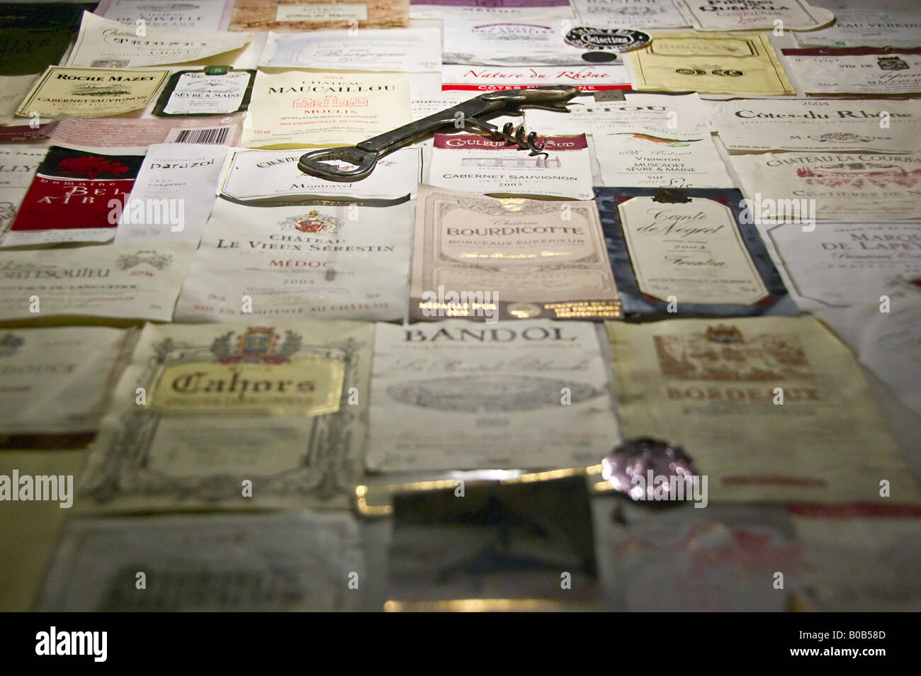 A corkscrew sits on top of many assorted wine labels Stock Photo - Alamy