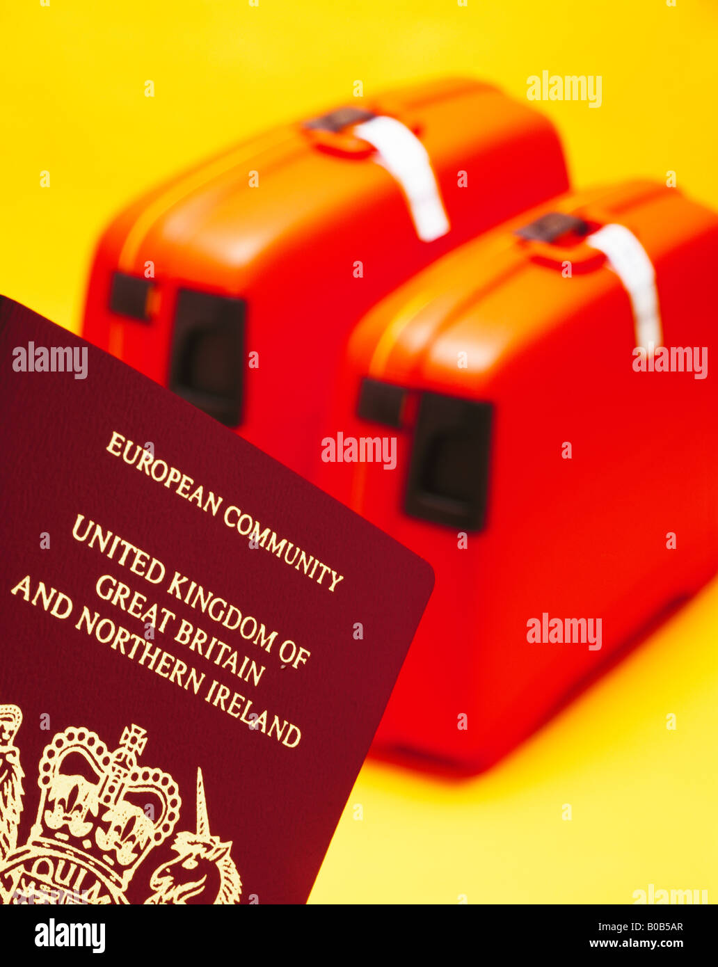 A British passport with 2 suitcases on a yellow background Stock Photo