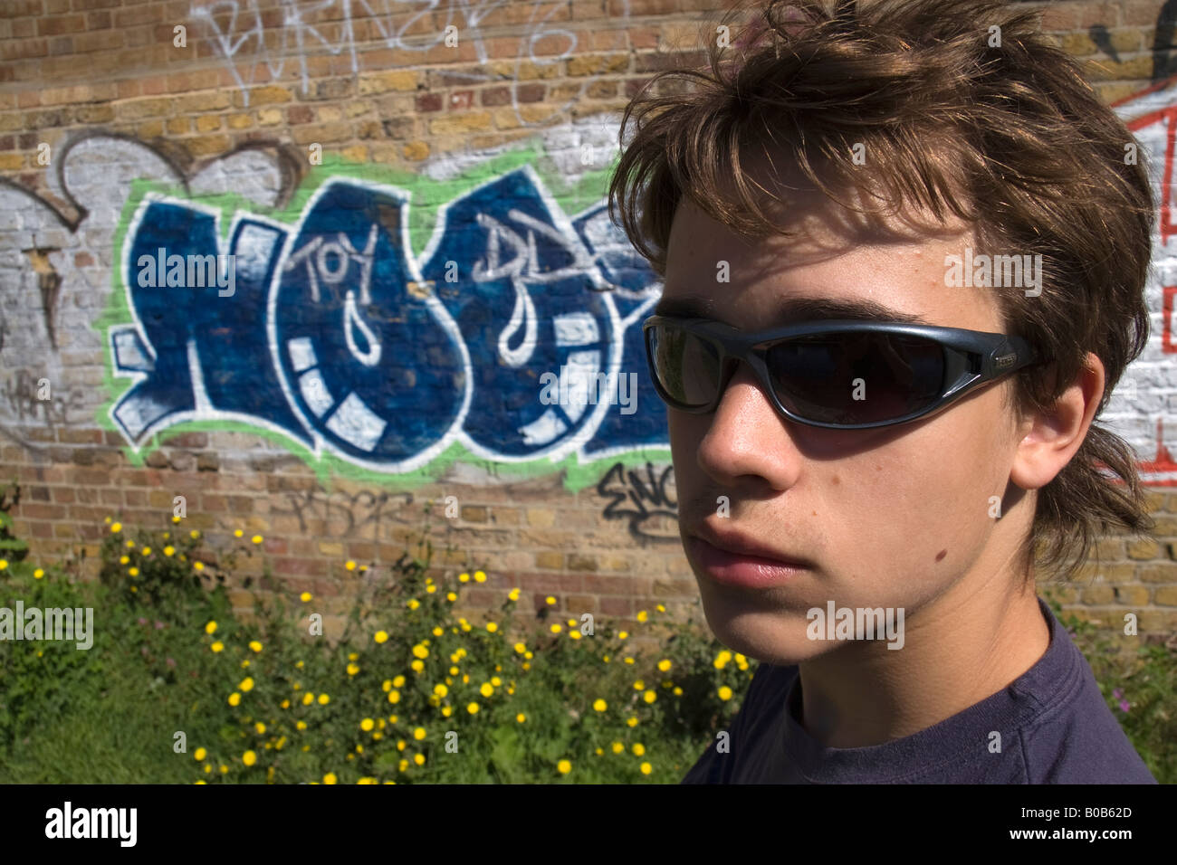 Portrait of cheerful handsome teenage boy wearing sunglasses and standing  on street beside metal fence. Smiling confident teenage boy in sunglasses  lo Stock Photo - Alamy