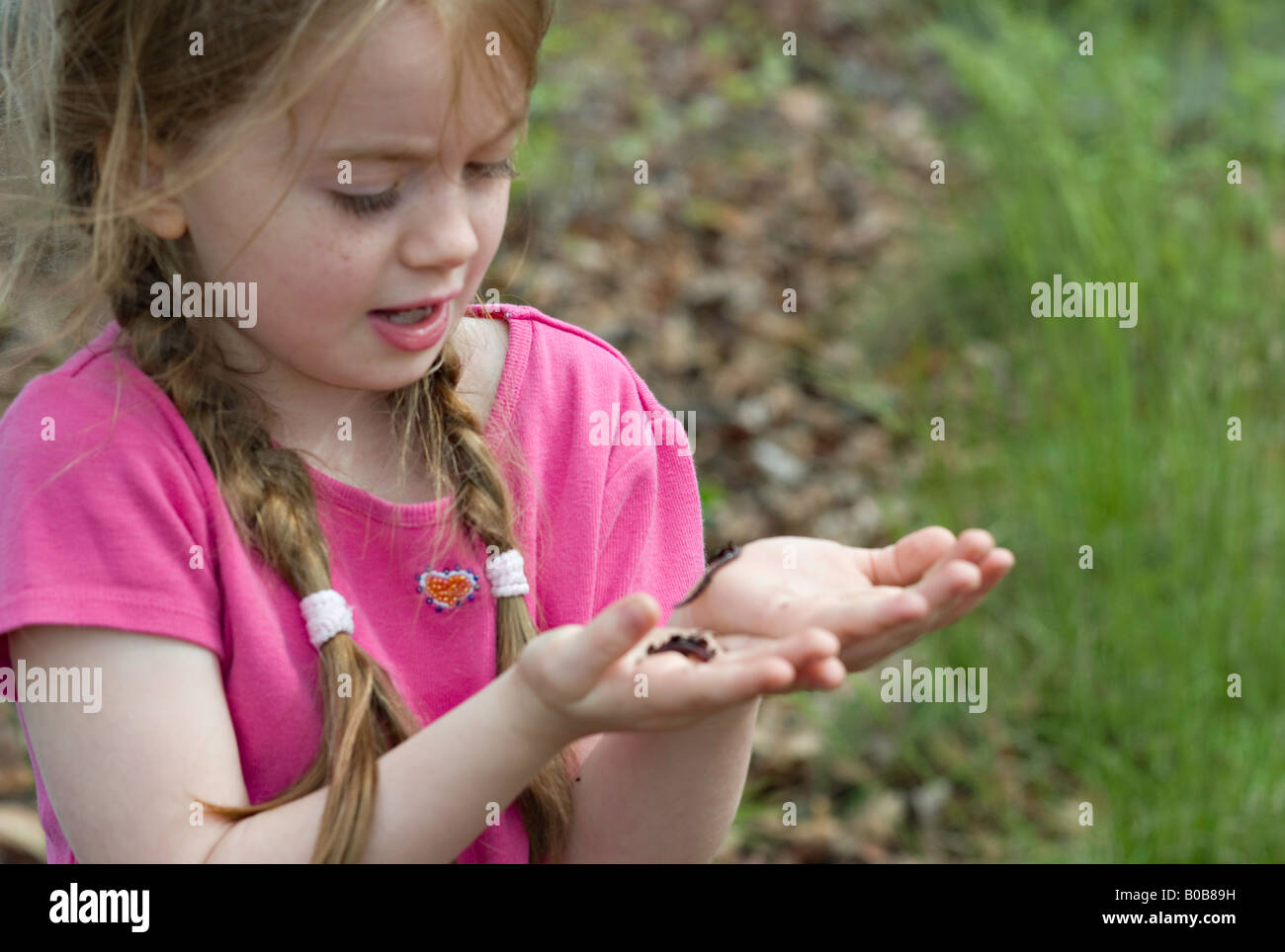 SOUTH CAROLINA YORK A beautiful young girl looking at earthworms crawling in her open hands in the middle of a forest Stock Photo