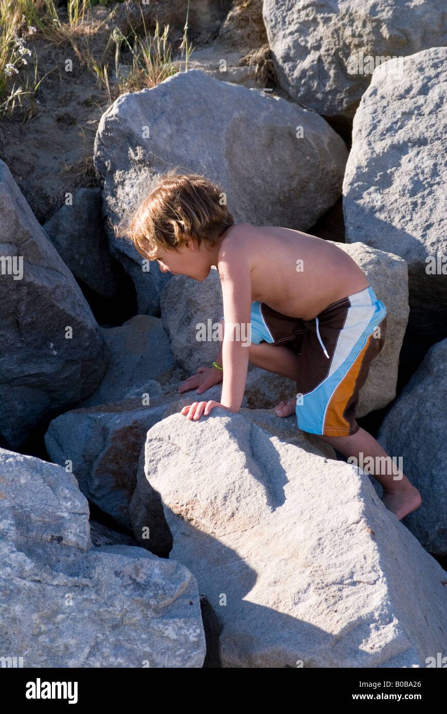 Boy in swimsuit plays on rocks Stock Photo - Alamy