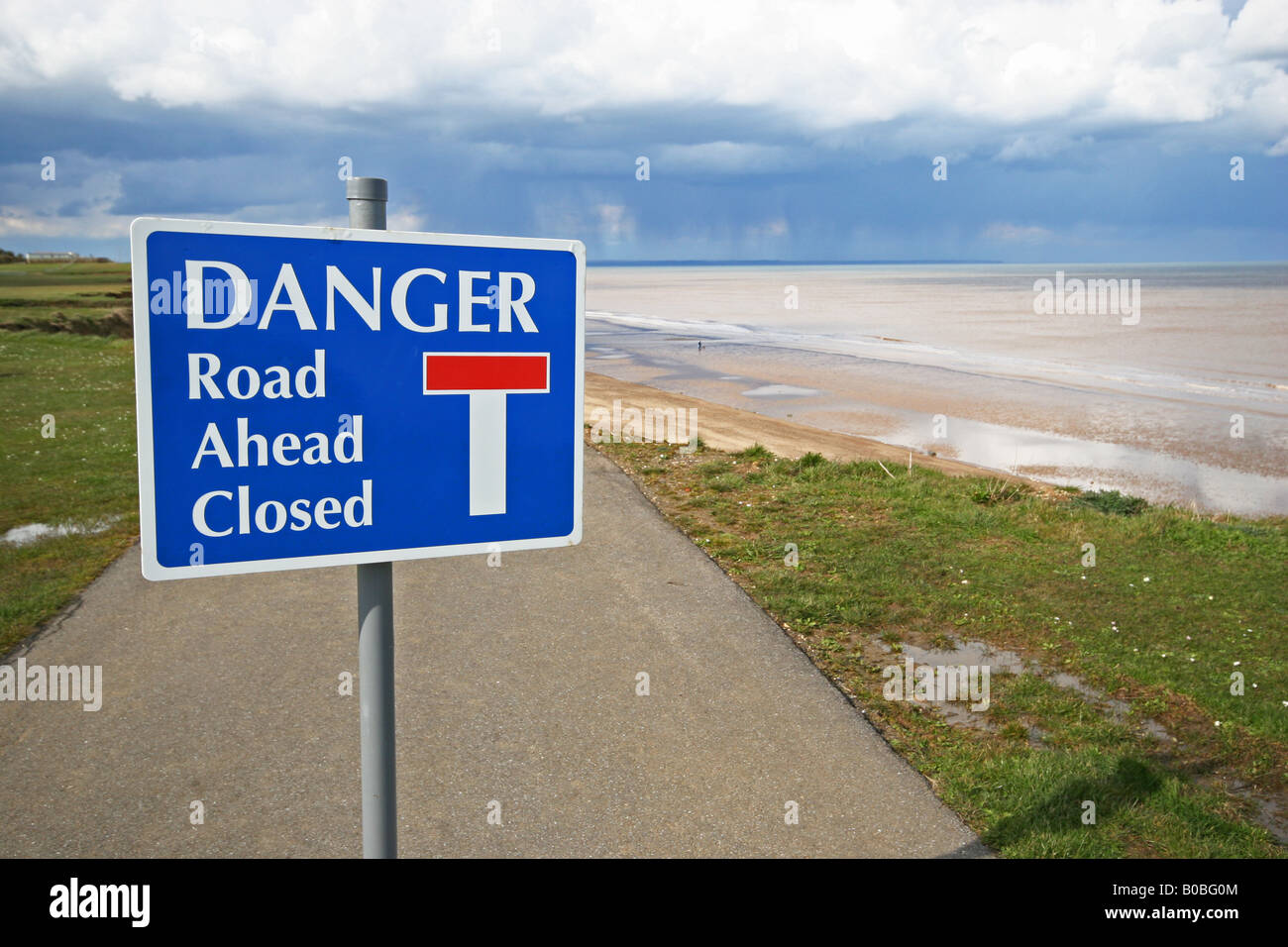 Danger sign on small metalled caravan site road where sea has eroded part of the cliff cutting the road. Stock Photo