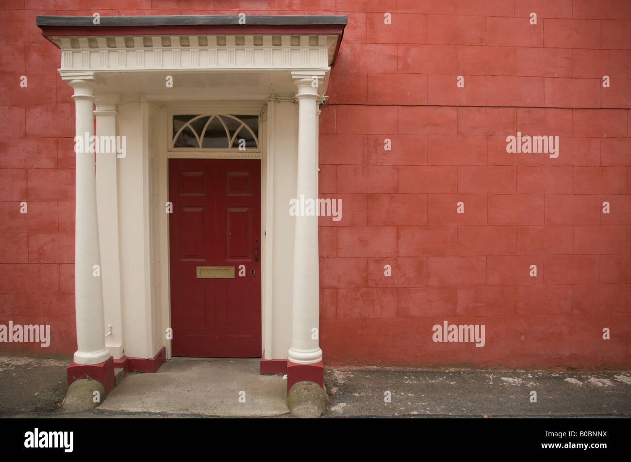 Restored Georgian doorway with columns and porch red painted wall Cardigan Town Wales UK Stock Photo