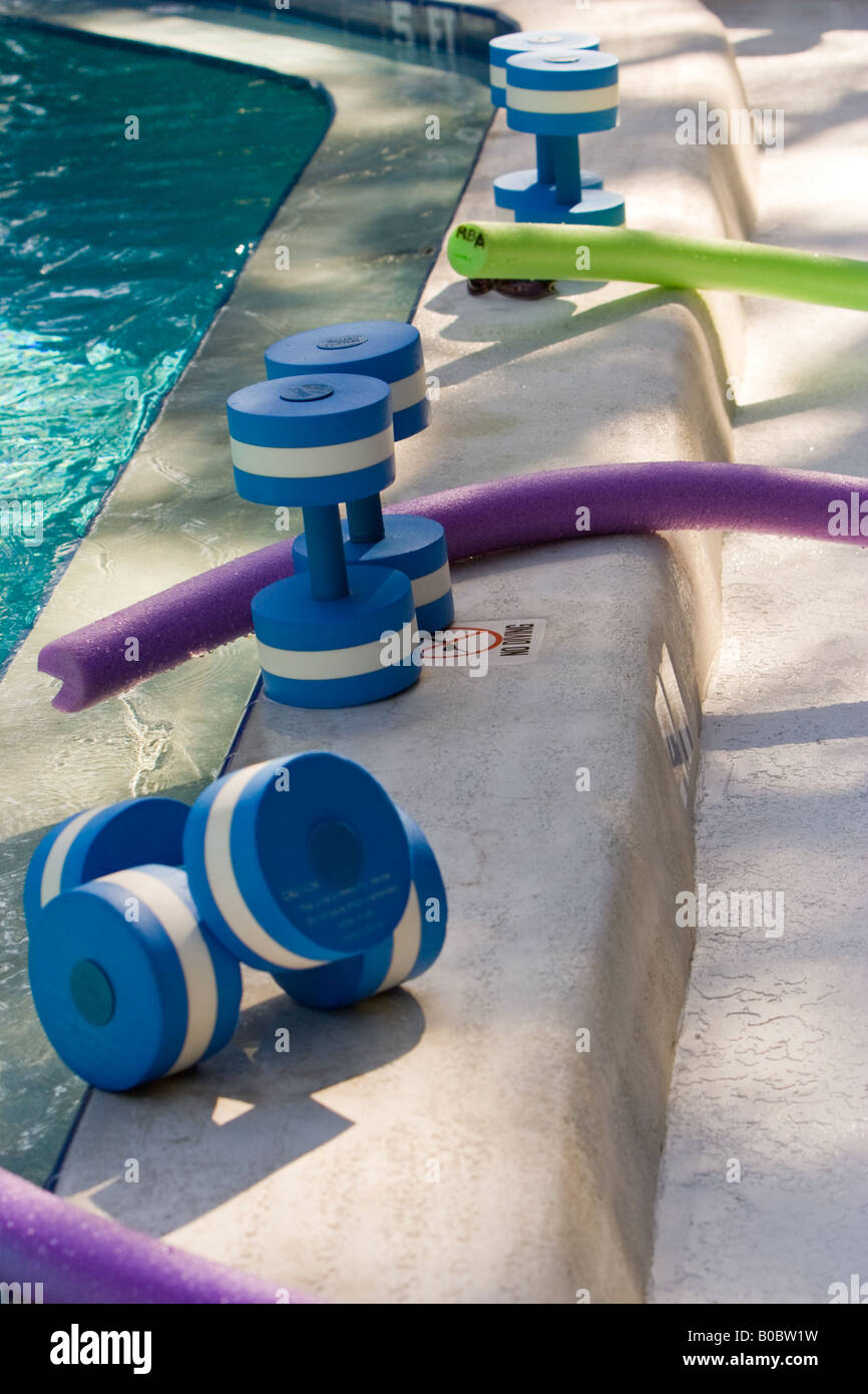 Water barbells and noodles wait at poolside as the water aerobics class