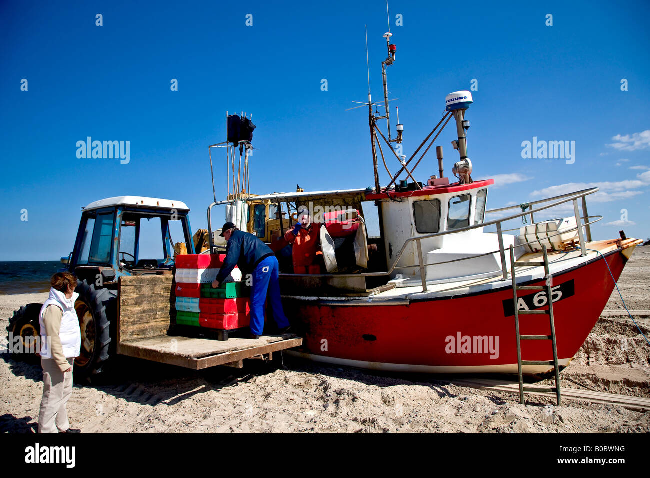 Unloading fish crates from the fishing cutter Stock Photo