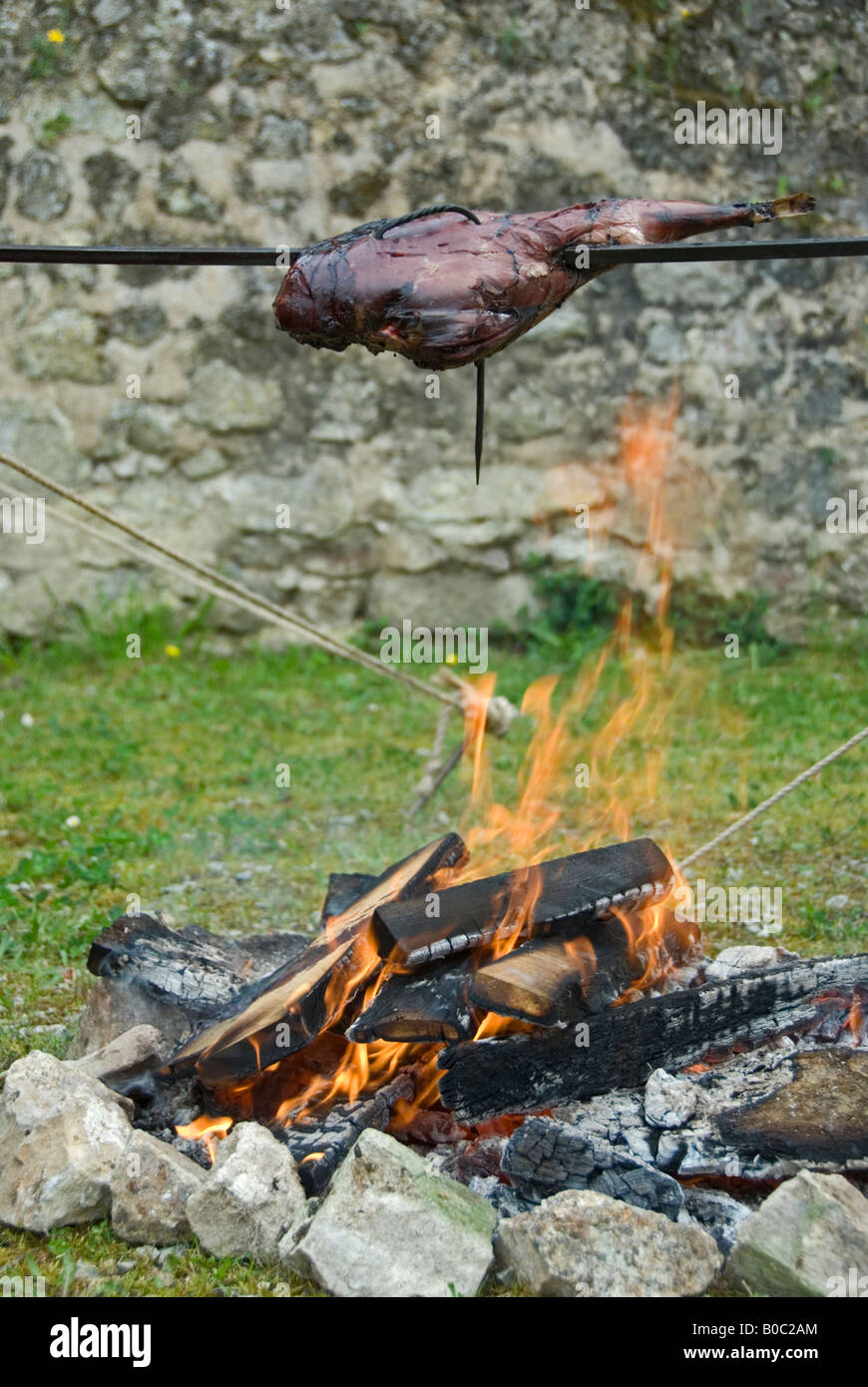 Stock photo of a piece of meat spit roasting over an open fire Stock Photo