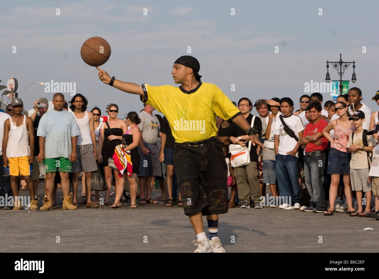 Hip-hop type performer with a basketball entertains the crowd on the boardwalk at Coney Island, Brooklyn, NY. Stock Photo