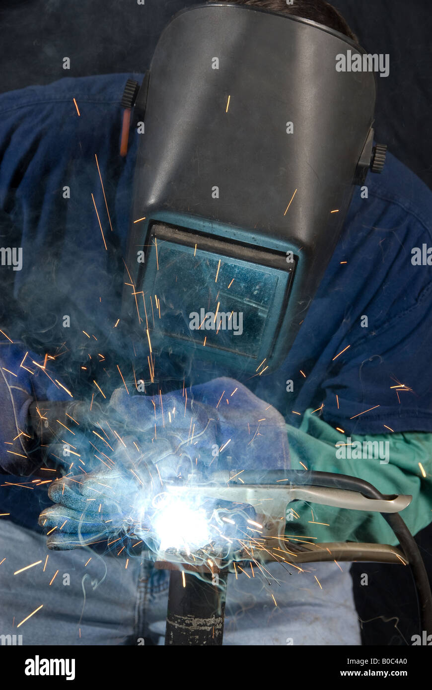 A welder fabricates a tool by attaching two pieces of metal Stock Photo