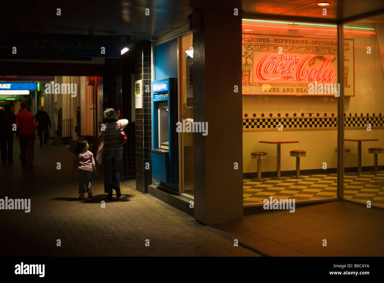 Mother and daughter walk past cafe at night Stock Photo - Alamy