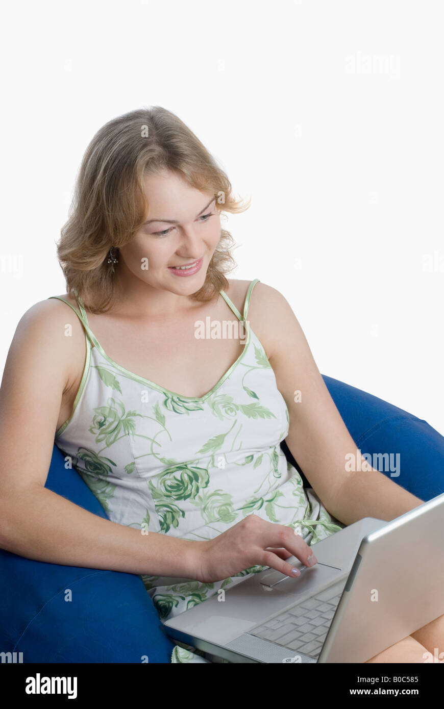 High angle view of a young woman sitting on a bean bag and using a ...
