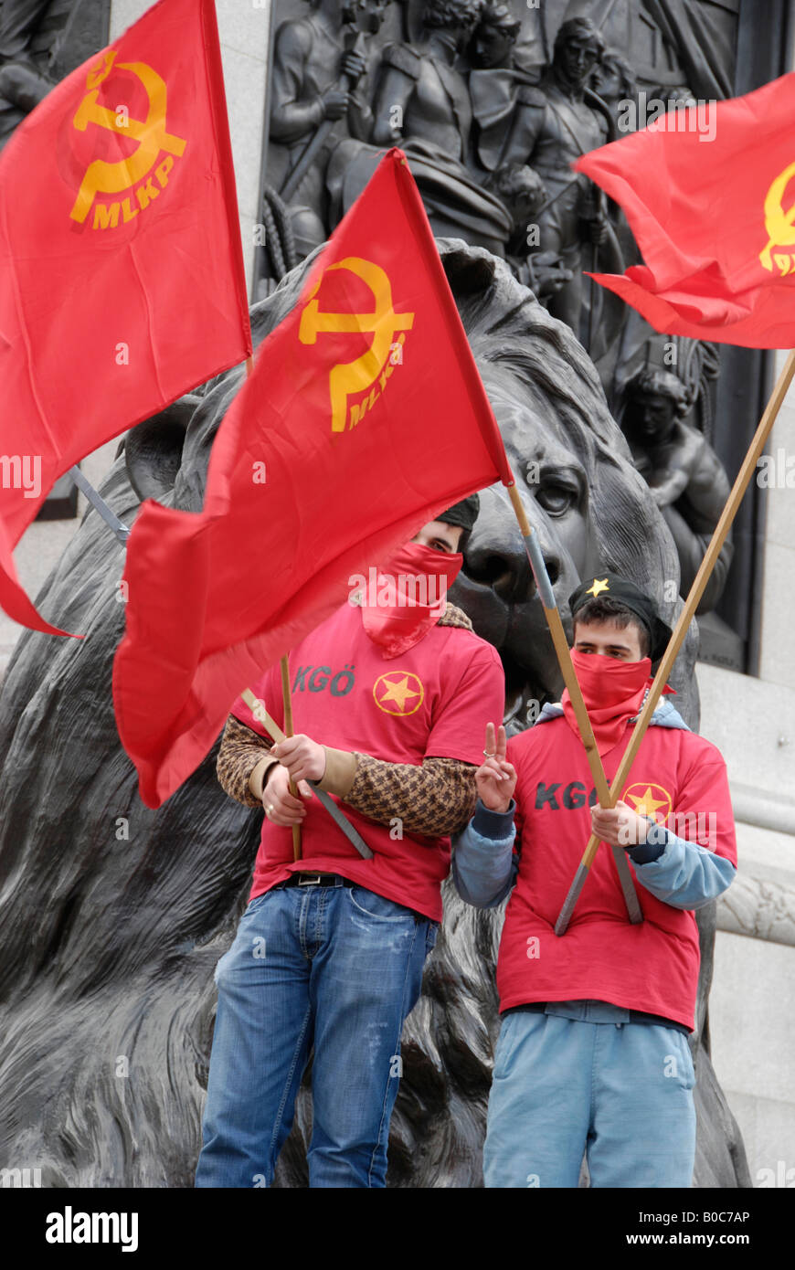 Two MLKP Turkish Marxist Leninist Communist Party members with red flags standing under lions in Trafalgar Square. Stock Photo