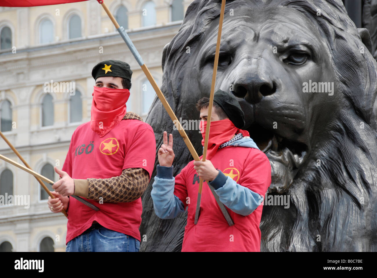 Two MLKP Turkish Marxist Leninist Communist Party members dressed in red standing under lions in Trafalgar Square Stock Photo