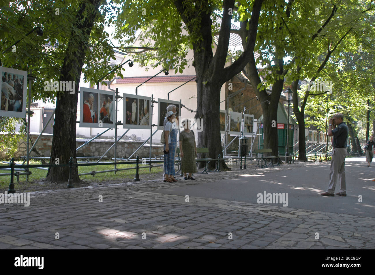 Polish people proud of their Pope; A man takes a picture of a couple in front of a photo-exhibition of Pope Johannes Paulus II i Stock Photo