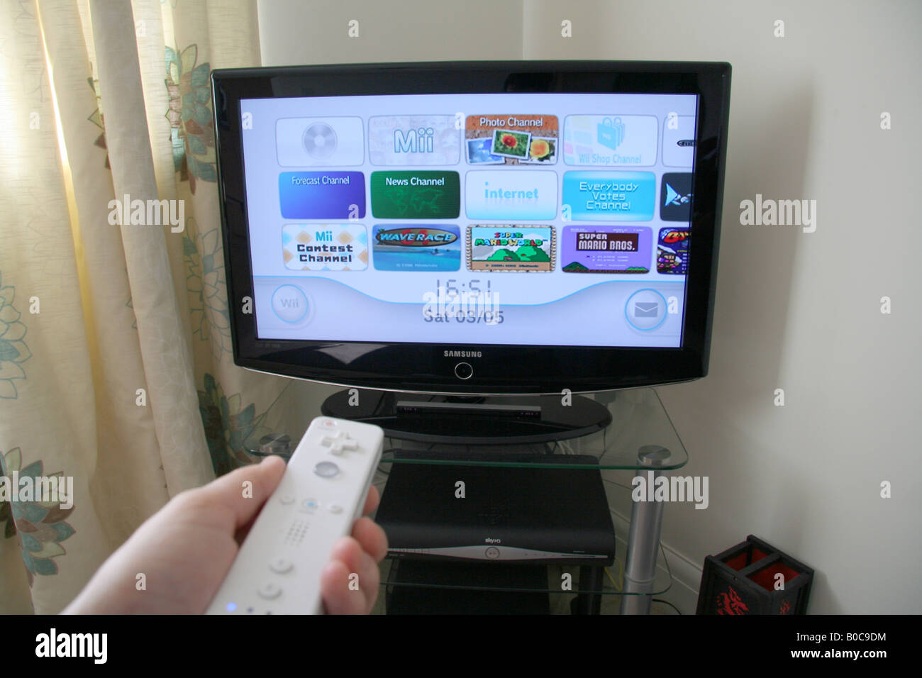 Hand Holding Nintendo wii controller pointing at the TV Stock Photo