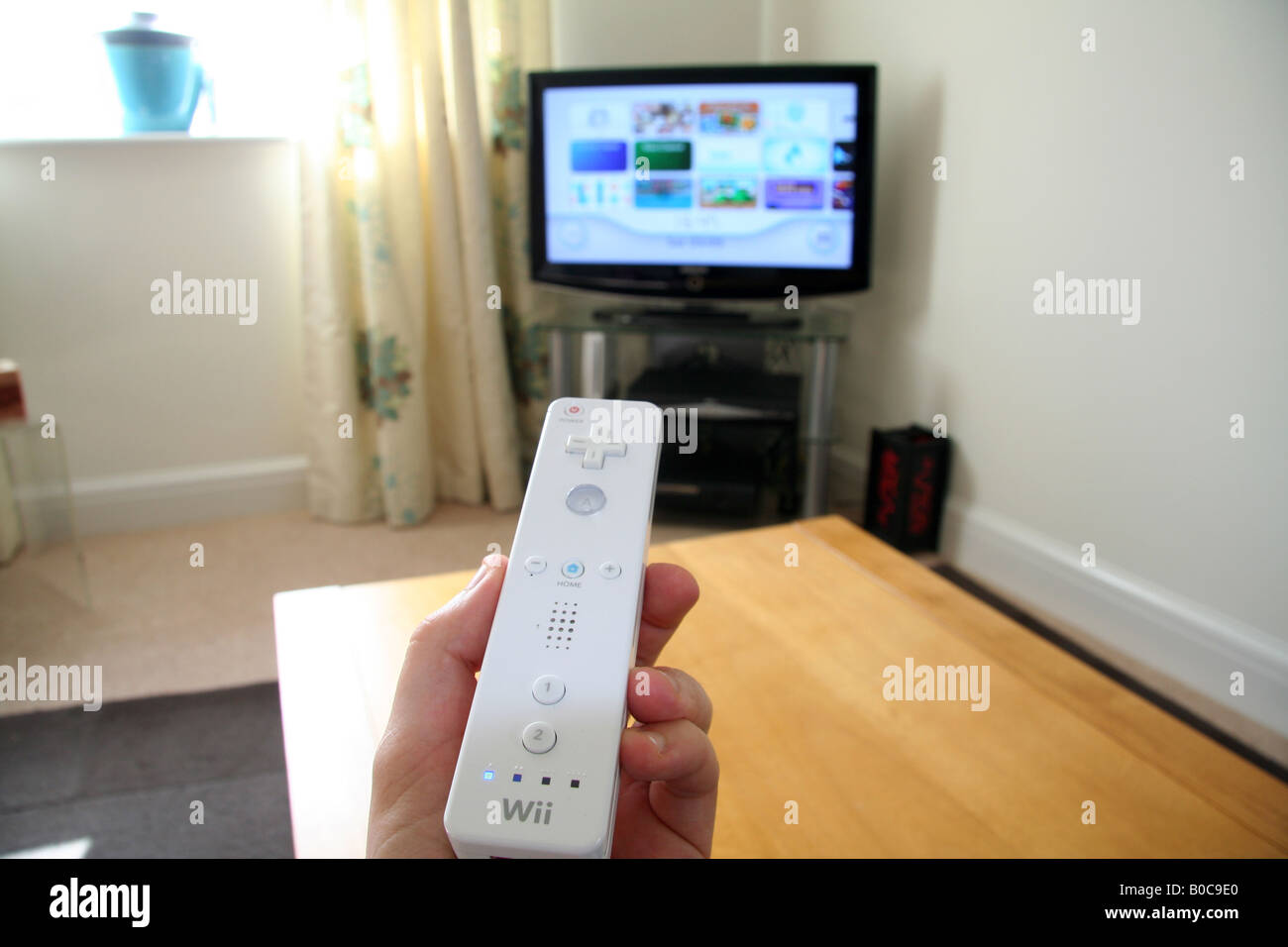 Hand Holding Nintendo wii controller pointing at the TV Stock Photo