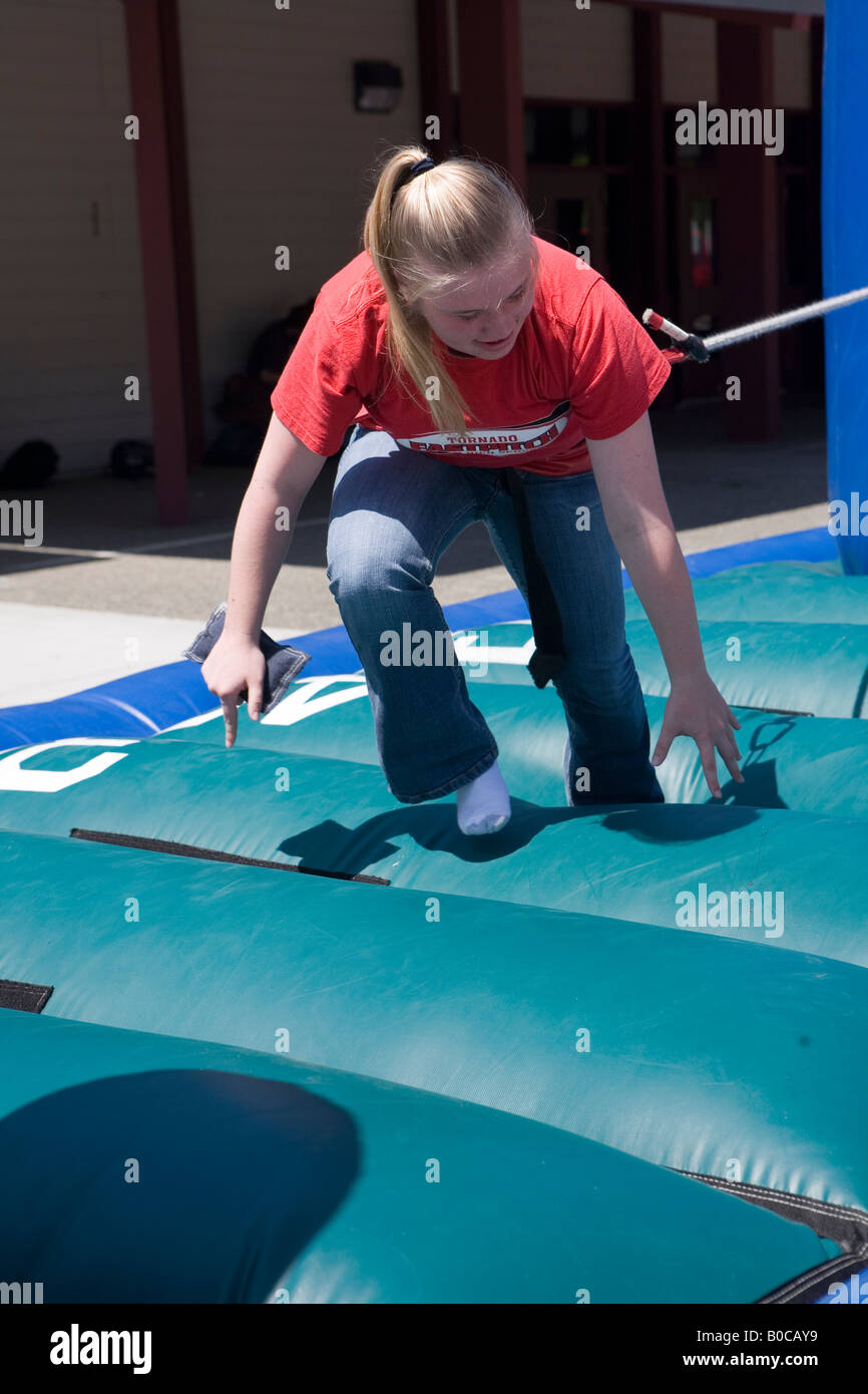 Image of a teenage girl running on One on One Bungee Pull inflatable interactive game struggling against her opponent Stock Photo