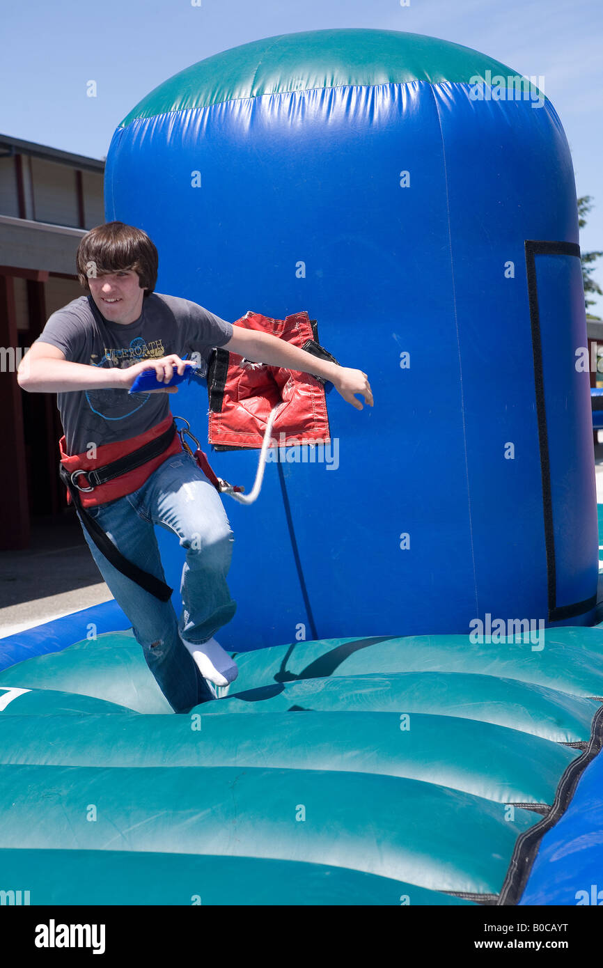 Image of a teenage boy running on One on One Bungee Pull inflatable interactive game Stock Photo