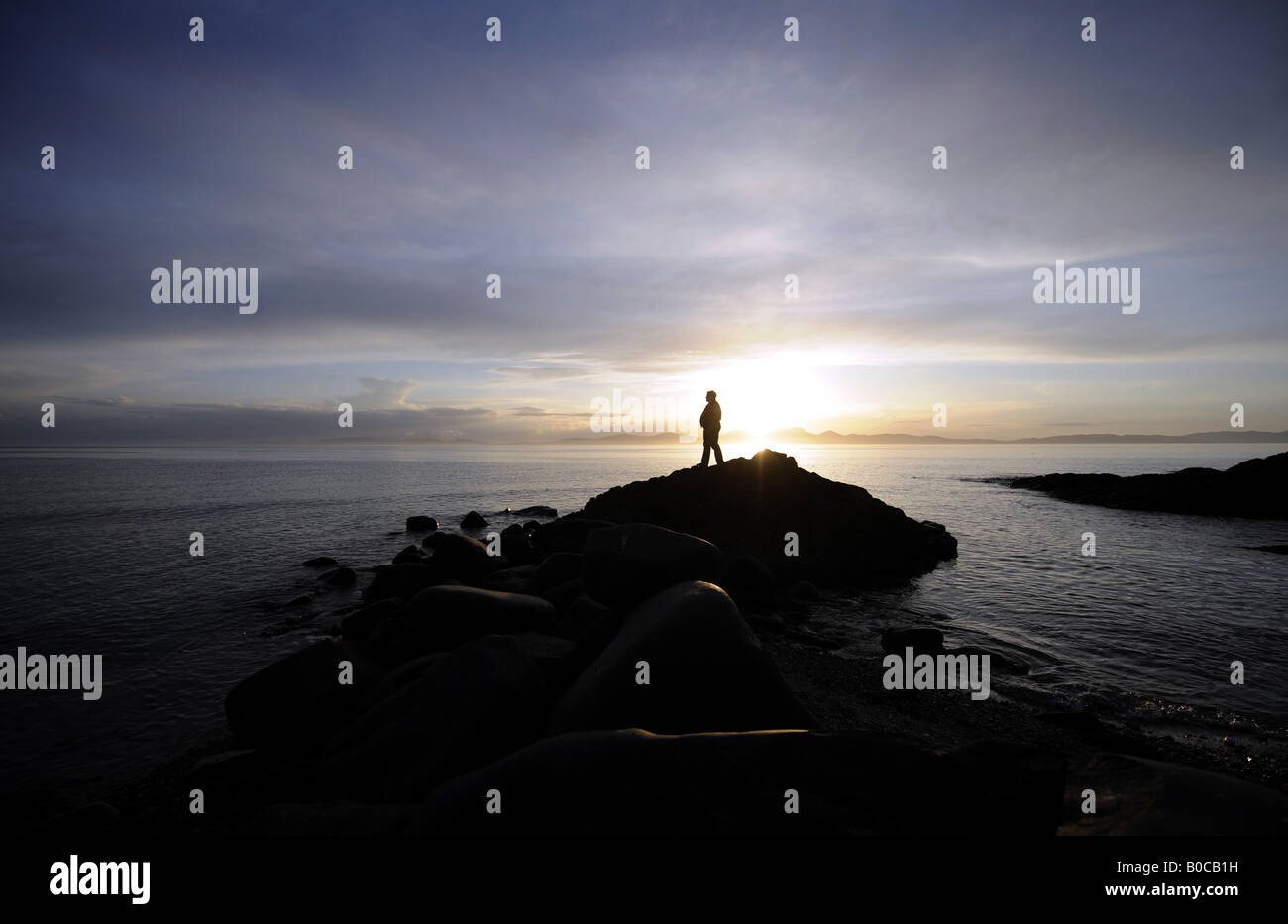 A PERSON LOOKING INTO A SUNSET FROM KINTYRE TO THE ISLE OF JURA IN NORTH WEST SCOTLAND,UK. Stock Photo