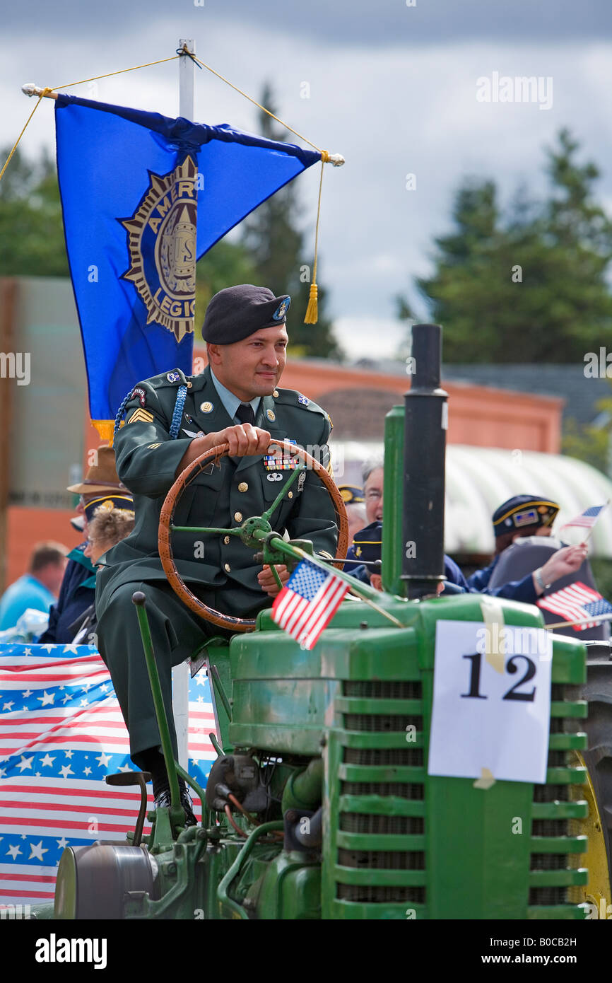 Image of an Army Officer driving a John Deere tractor decorated with American Flags in a small town Patriot Day Parade Stock Photo