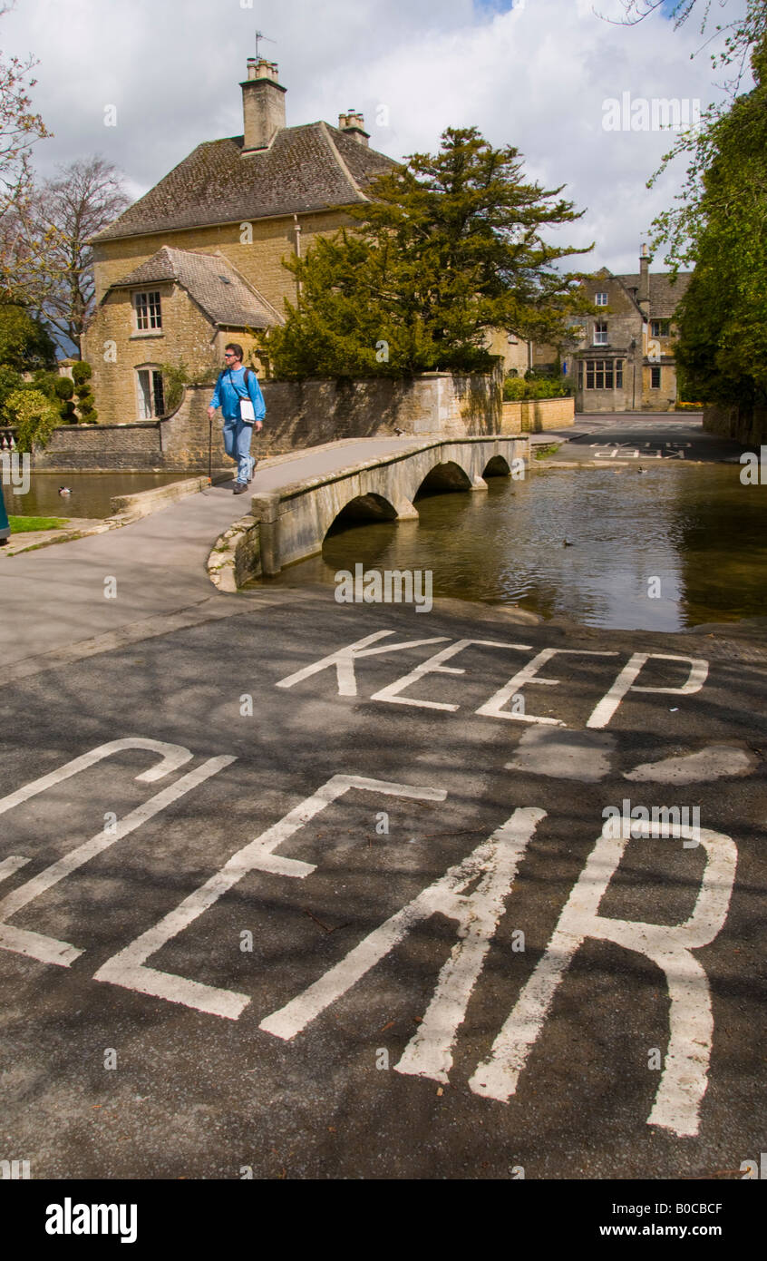 Ford thru River Windrush with walker crossing bridge in village of Bourton on the Water Cotswolds Gloucestershire England UK EU Stock Photo