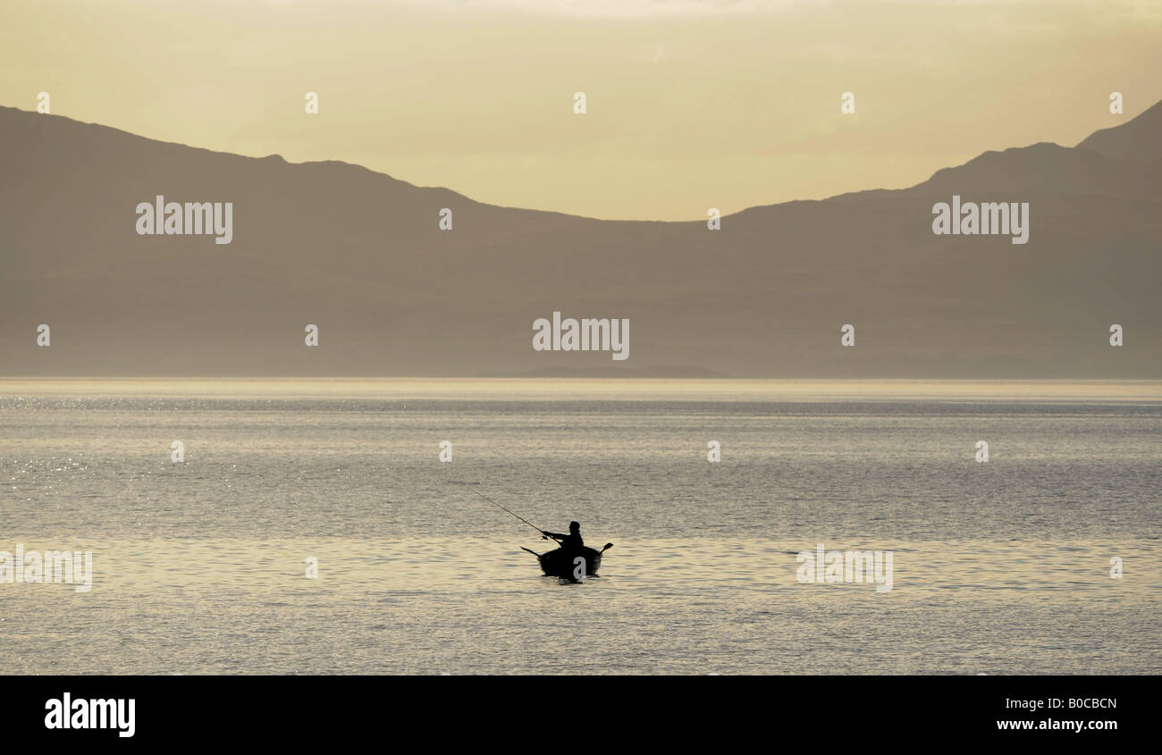 A FISHERMAN FISHES FROM A BOAT IN THE WATERS OFF KINTYRE,NORTH WEST SCOTLAND,LOOKING OUT TOWARDS THE ISLAND OF JURA.UK Stock Photo