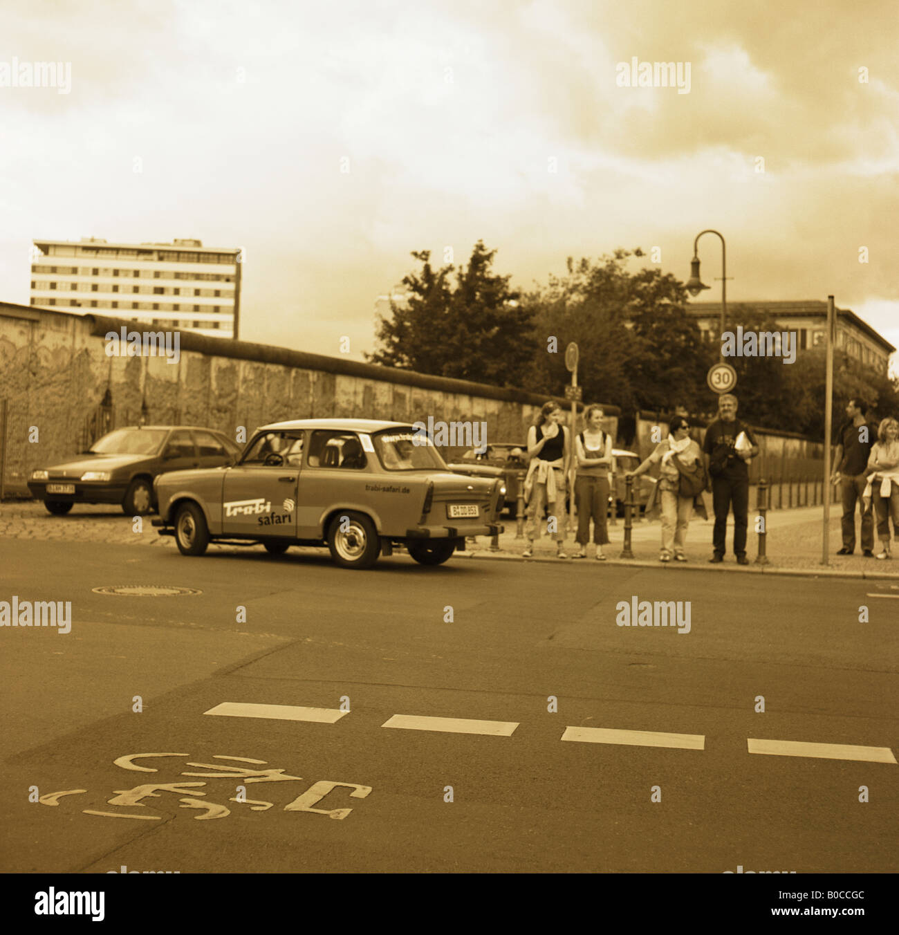 Trabi and car passing Berlin wall Stock Photo