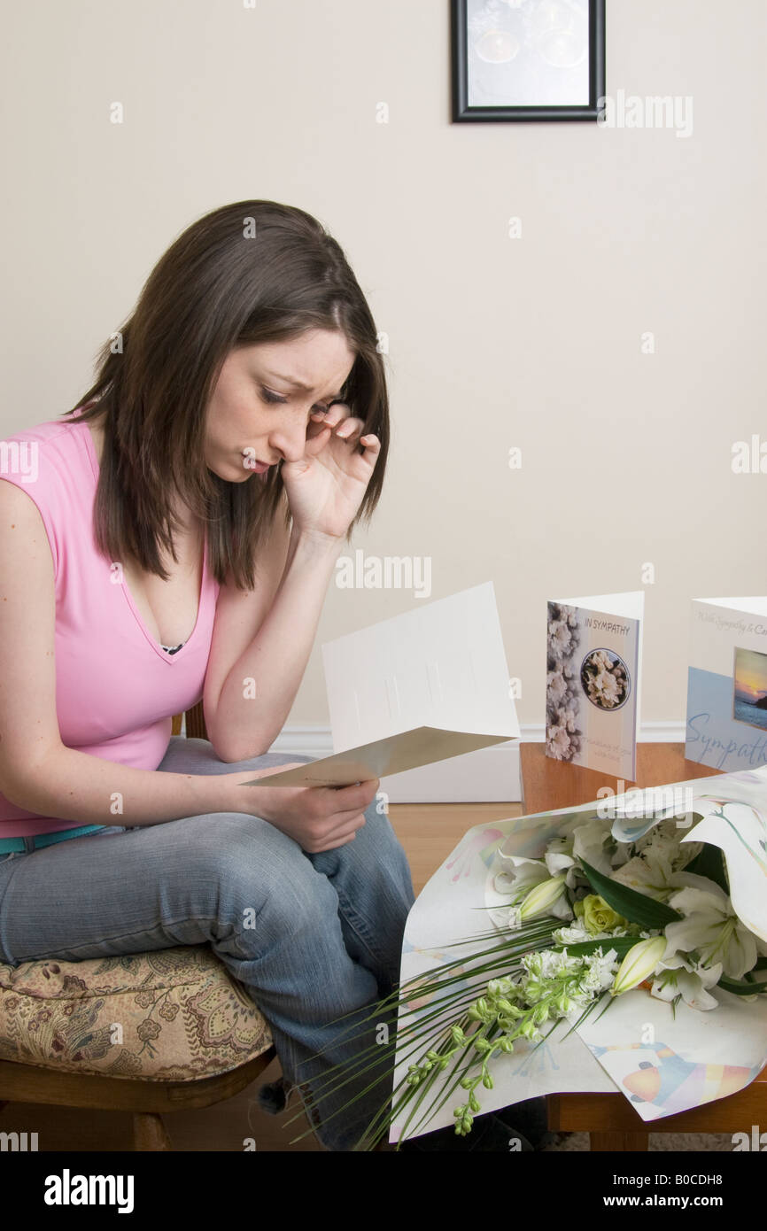 Young woman possibly bereaved or widowed reading sympathy cards from well wishers Stock Photo