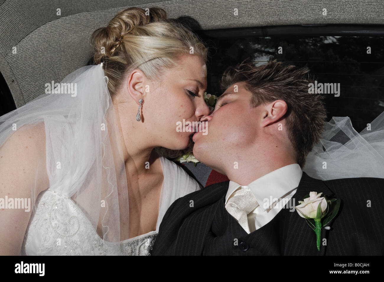 Bride and groom kissing in a wedding car Stock Photo