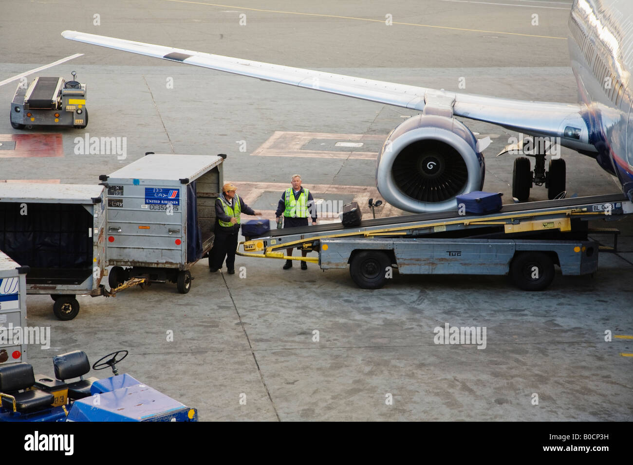 Ground crew loading checked baggage onto an airplane San Francisco International Airport California USA Stock Photo