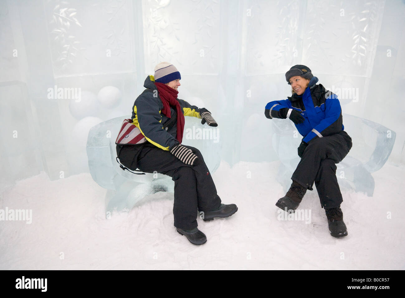 Two women are sitting on armchairs made of ice inside the Jukkasjarvi icehotel in northern Sweden Stock Photo