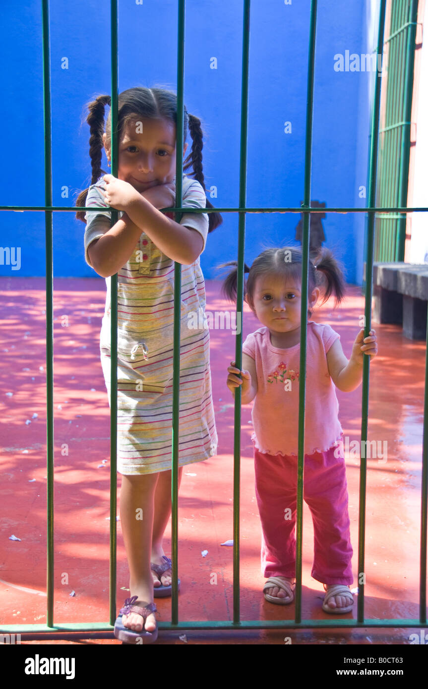 Two little girls stood outside a metal gate at Frida Kahlo's house, known as the Blue House. in Mexico City Stock Photo